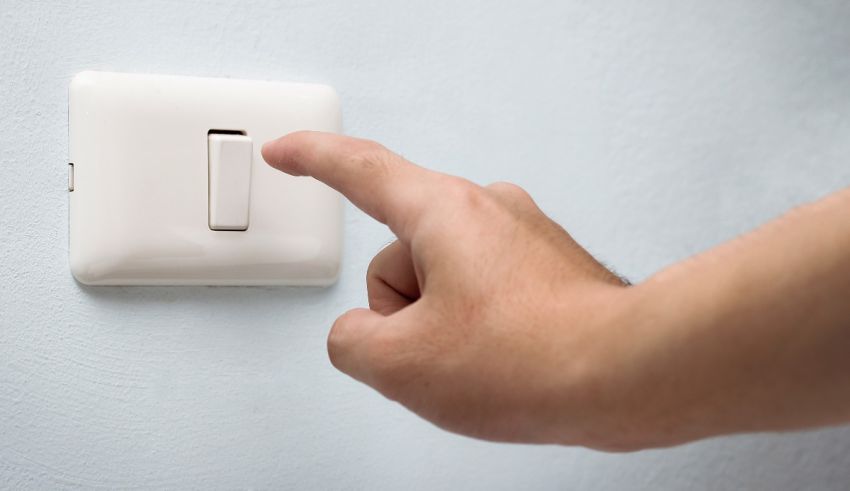 A hand is pointing at a light switch.