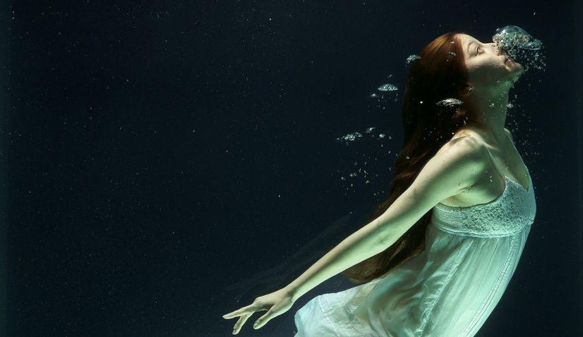 A woman in a white dress under water.