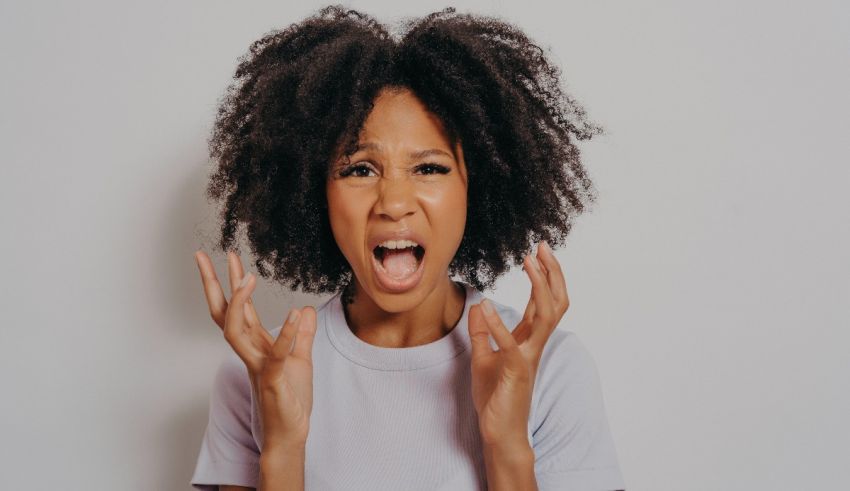A black woman with afro hair is screaming in front of a white background.