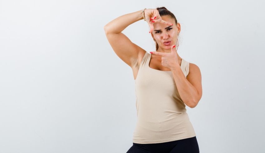 A woman in a beige tank top is making a fist gesture.