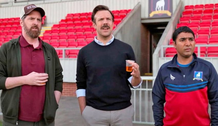 Three men standing next to each other in a stadium.