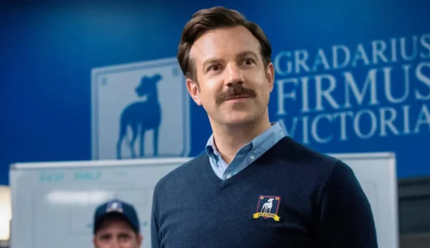 A man with a mustache standing in front of a blue sign.