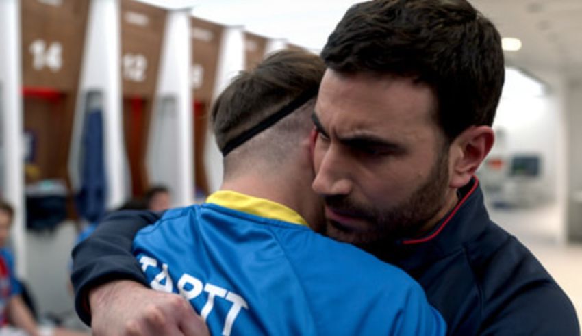 A man is hugging another man in the locker room.