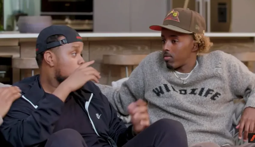 Three men sitting on a couch talking to each other.