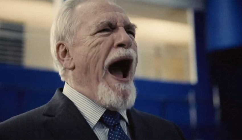 An older man in a suit and tie shouting.