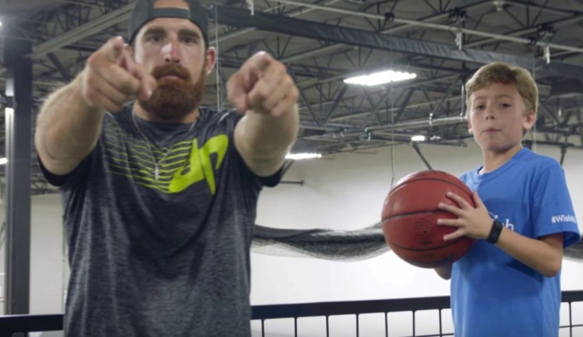 A man with a beard is pointing at a boy holding a basketball.