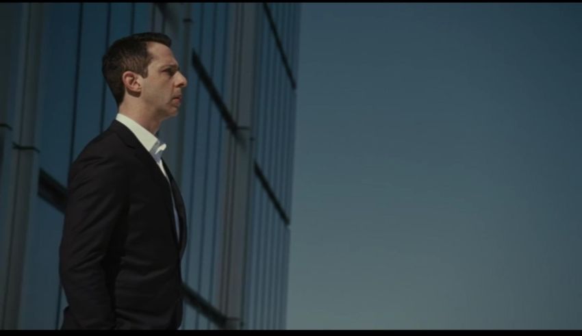 A man in a suit is standing in front of a building.