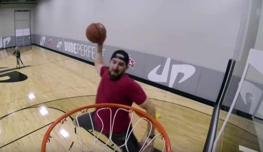 A man dunks a basketball in a gym.