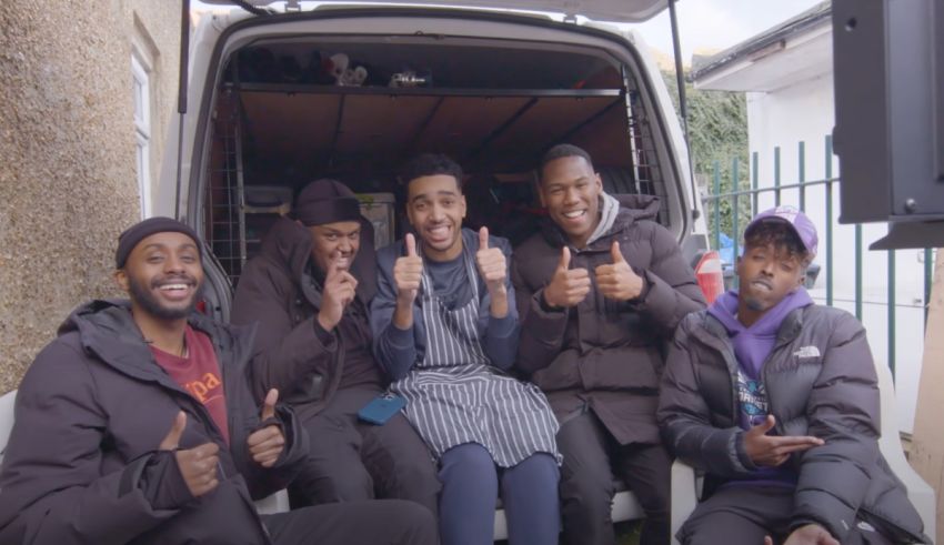 A group of men sitting in the back of a van giving thumbs up.