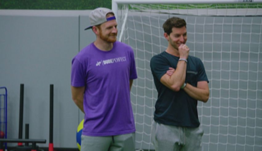 Two men standing in front of a soccer goal.