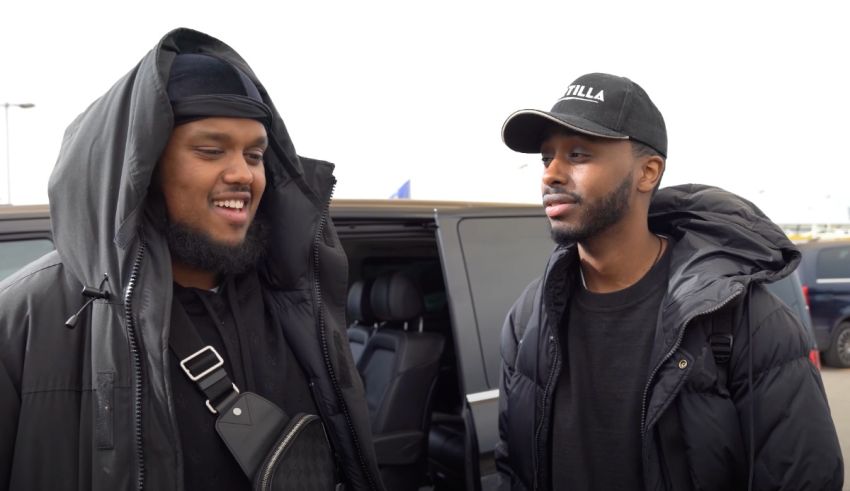 Two men standing next to each other in front of a car.