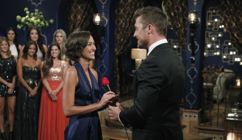The bachelor contestant is holding a rose in front of a group of people.