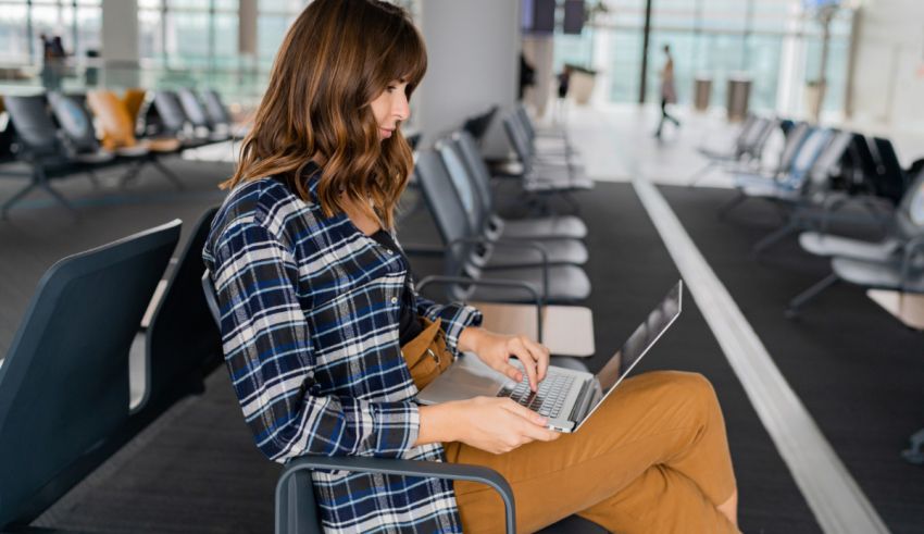 A woman sitting in an airport using her laptop.