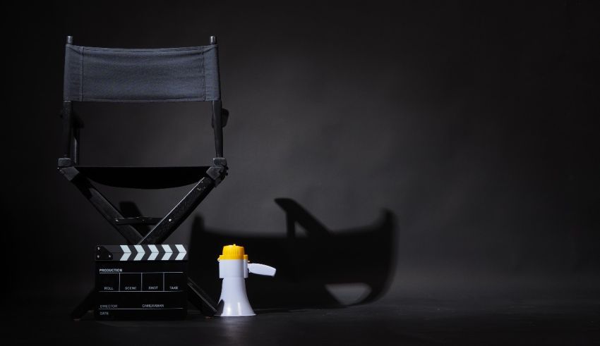 A black director's chair with a film clap on a black background.