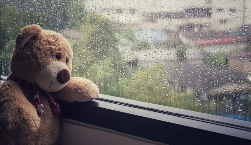 A teddy bear sitting on a window sill.
