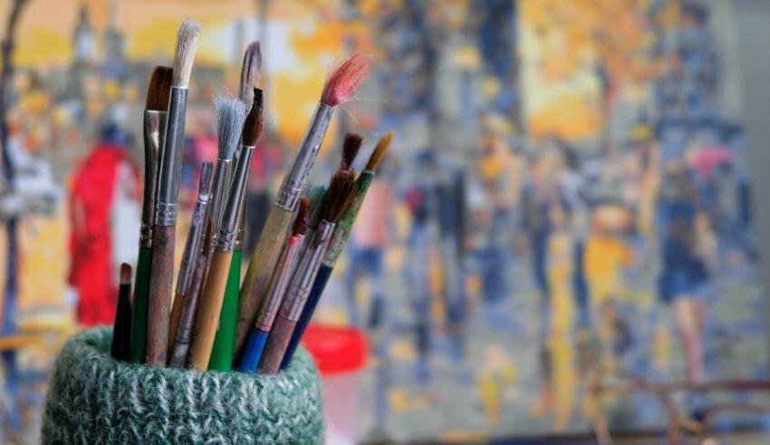 A group of paint brushes in front of a painting.