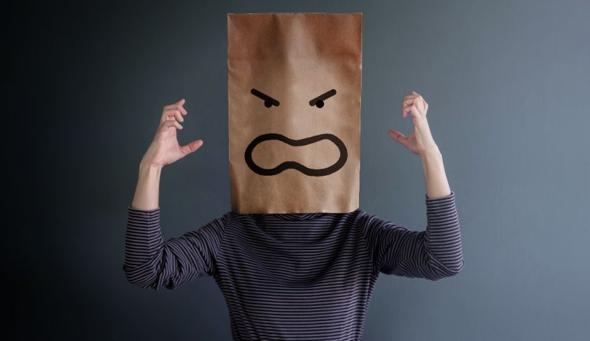 A woman wearing a brown paper bag with an angry face on it.