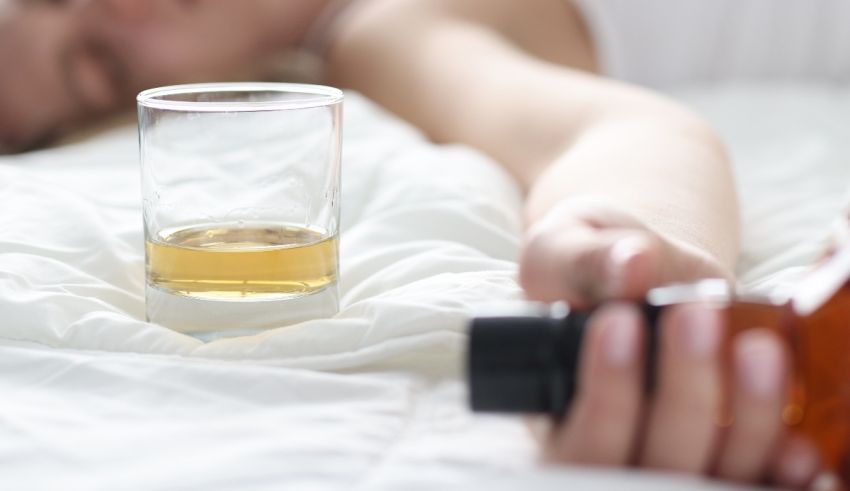 A woman laying on a bed with a glass of alcohol.