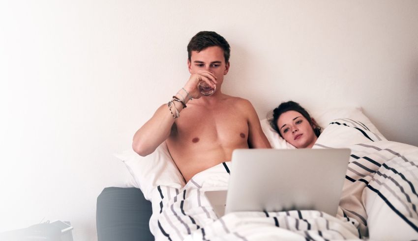A man and woman laying in bed with a laptop.