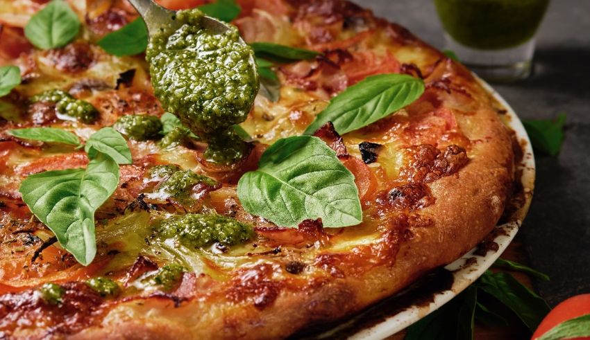 A pizza with basil and tomatoes on top.