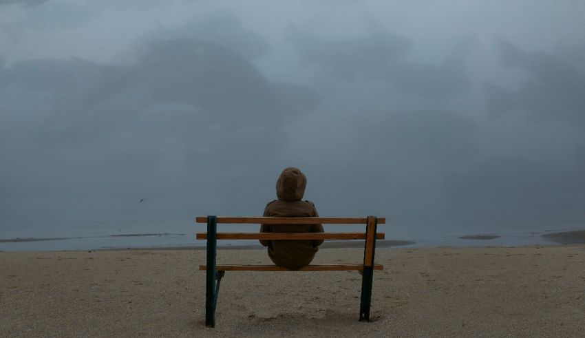 A person sitting on a bench on a beach.