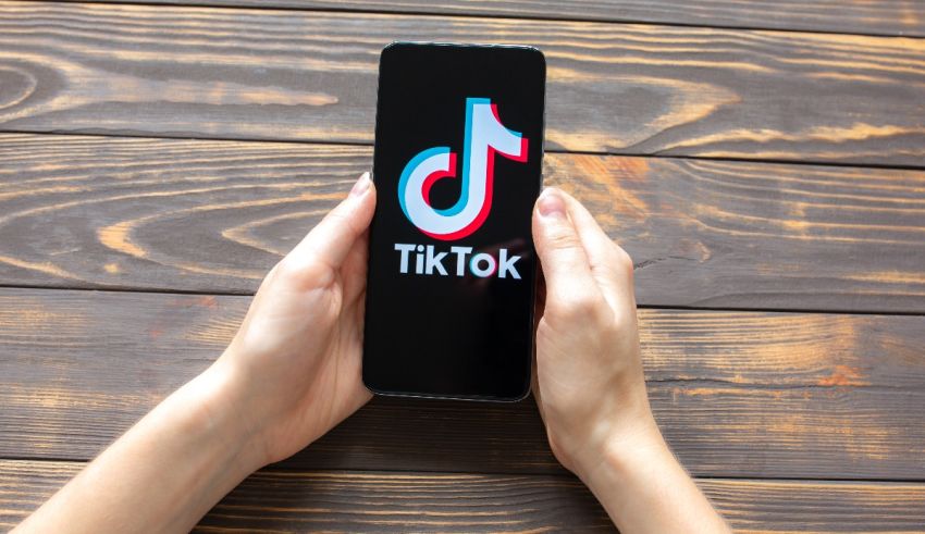 A person holding a phone with the tiktok logo on it.