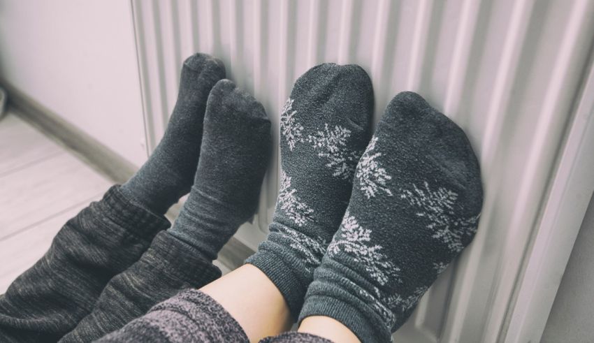 A pair of feet standing next to a radiator.