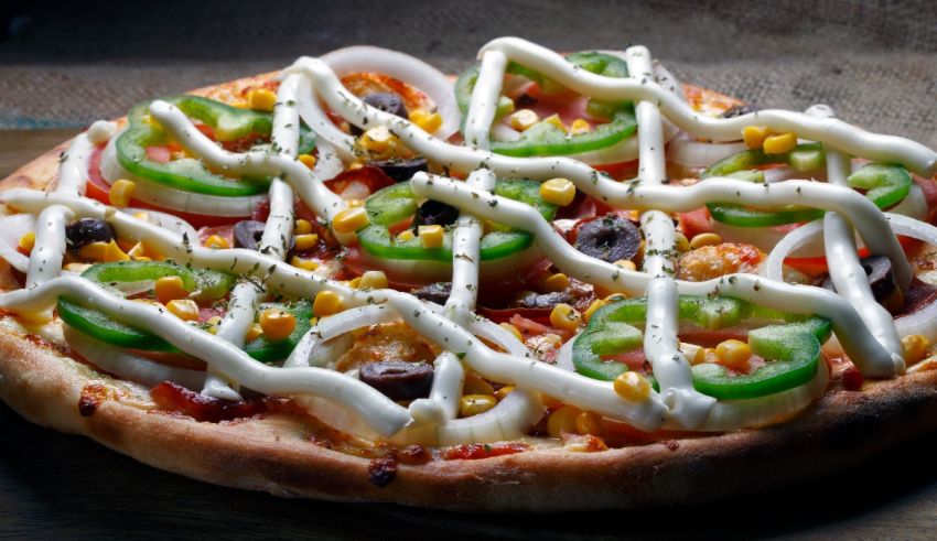 A pizza with peppers, onions, and corn on it.