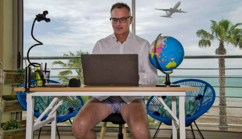 A man sitting at a desk with a laptop in his underwear.