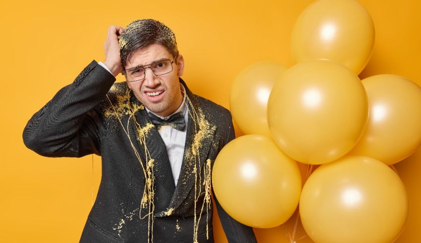A man in a tuxedo with balloons on a yellow background.