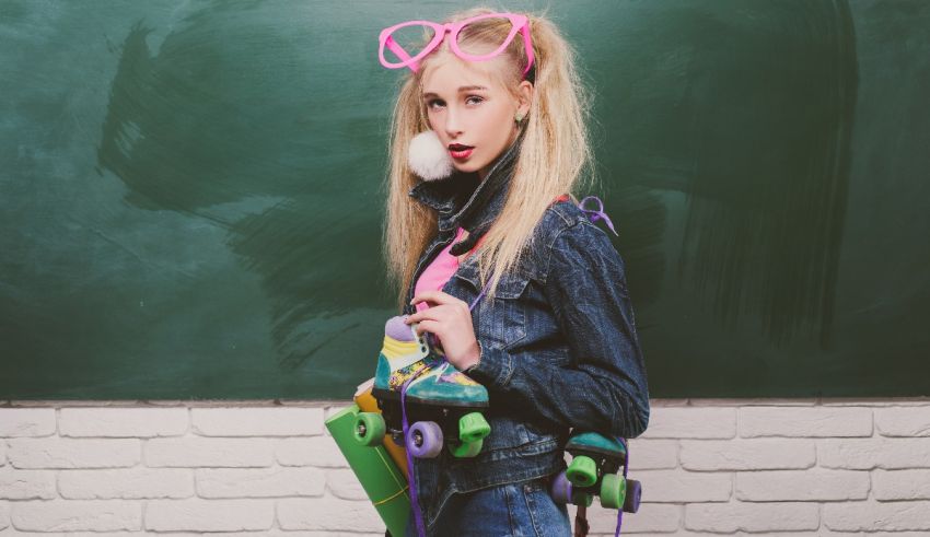 A girl wearing glasses and a skateboard in front of a chalkboard.