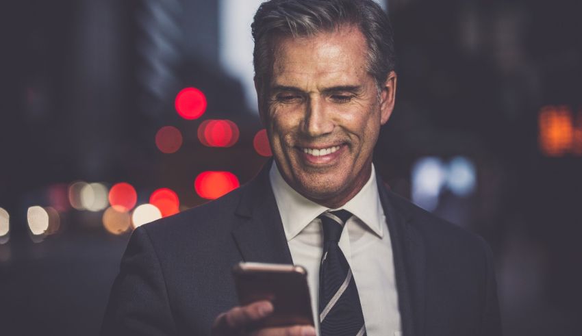 A man in a suit is looking at his phone at night.