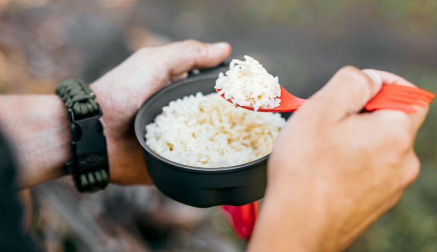 A person holding a bowl of rice with a red spoon.