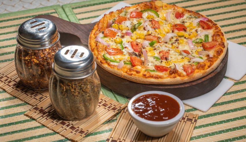 A pizza is sitting on a table next to salt and pepper shakers.