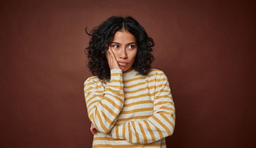 A woman in a striped sweater with her hand on her face.