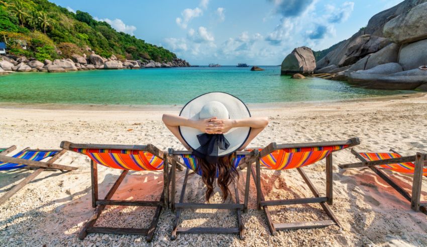 A woman relaxes in a lounge chair on a beach.