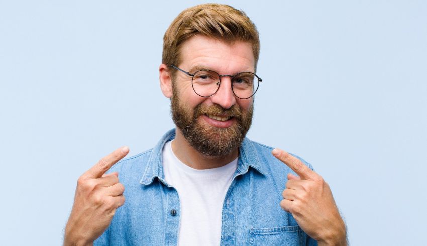 A man with glasses and a beard pointing his finger.