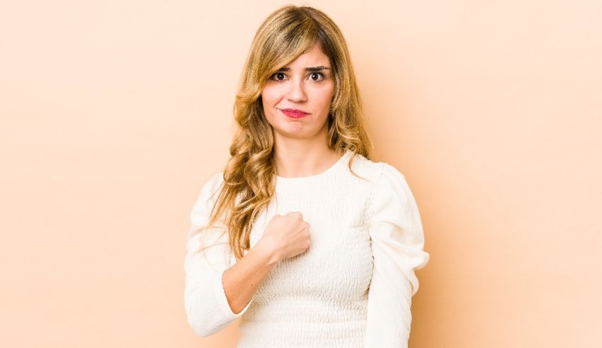 A woman with a clenched fist posing against a beige background.