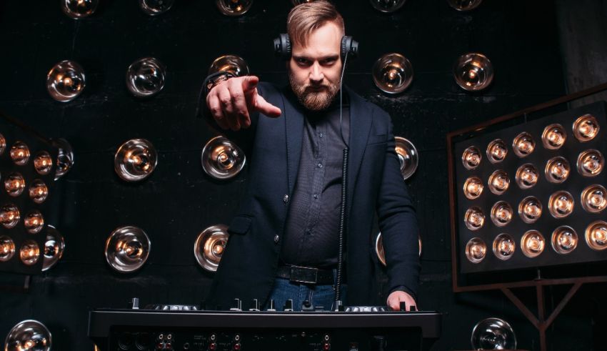 A bearded dj with headphones in front of a set of lights.