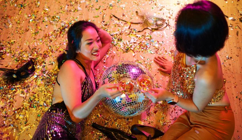 Two women playing with confetti on the floor.