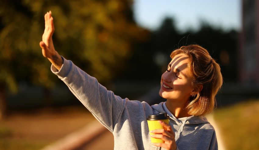 A woman is waving her hand while holding a cup of coffee.