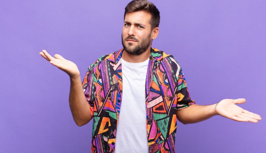 A man in a colorful shirt with his hands outstretched against a purple background.