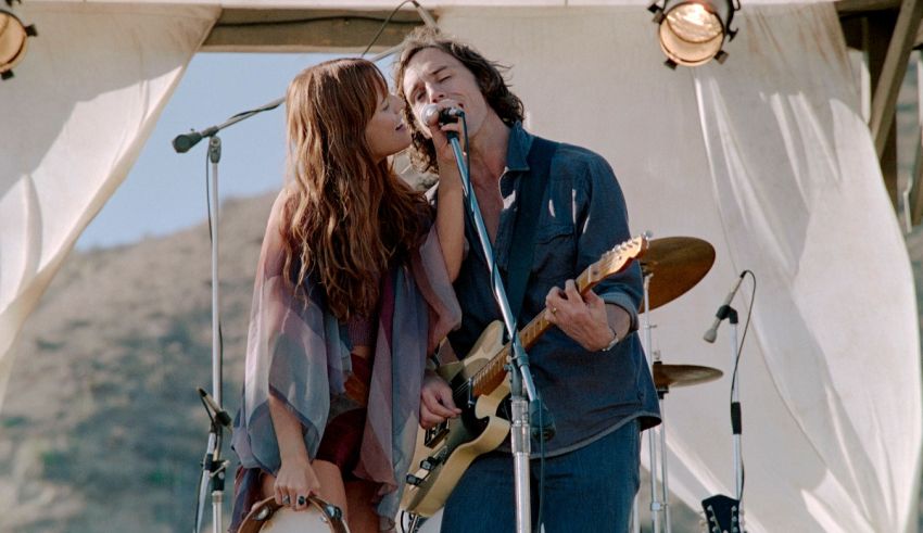 A man and a woman singing on stage in front of a tent.