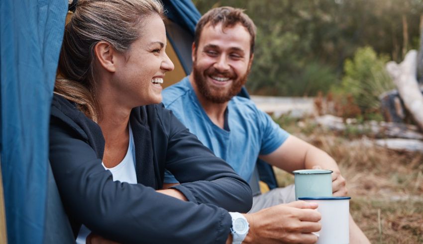 A man and woman sitting in a tent with a cup of coffee.