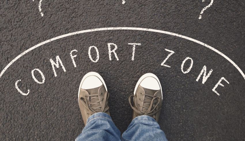 A person's feet standing on a road with the word comfort zone written on it.