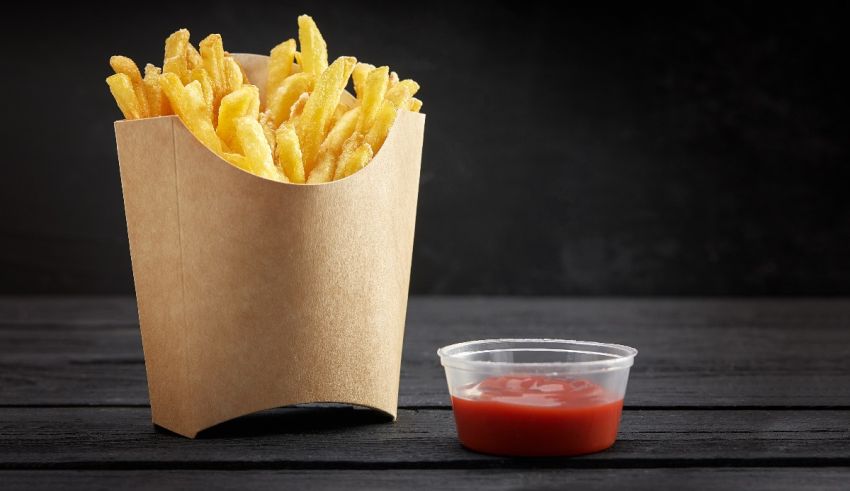 French fries in a paper bag with ketchup.