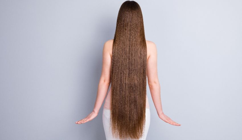 A woman with long hair standing on a gray background.