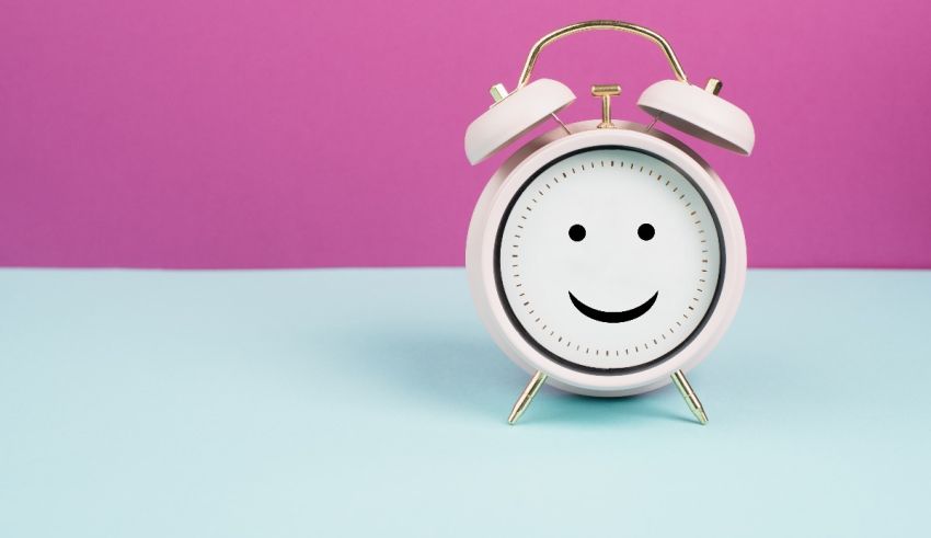 An alarm clock with a smiley face on a pink and blue background.