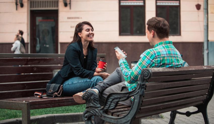 Two people sitting on a bench talking to each other.