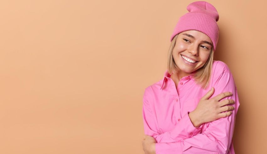 A young woman wearing a pink beanie posing on a beige background.